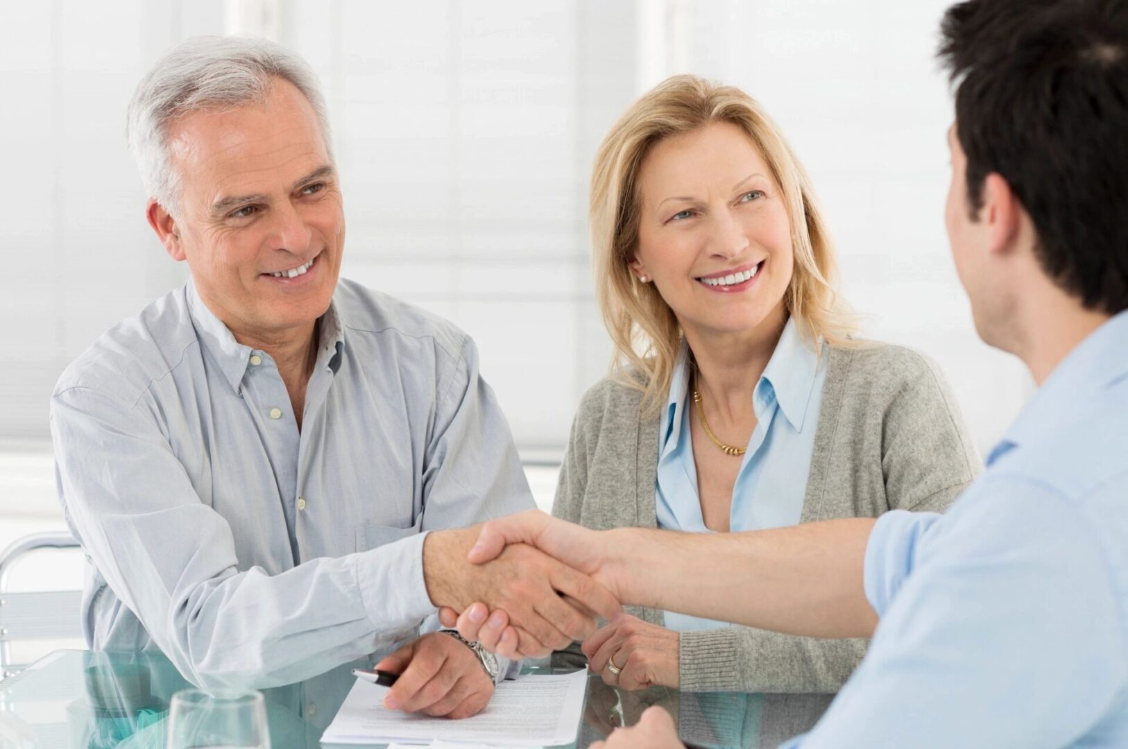 A man and woman shaking hands over a table.