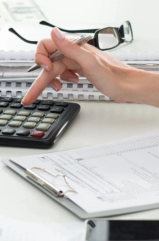 A person using a calculator on top of papers.